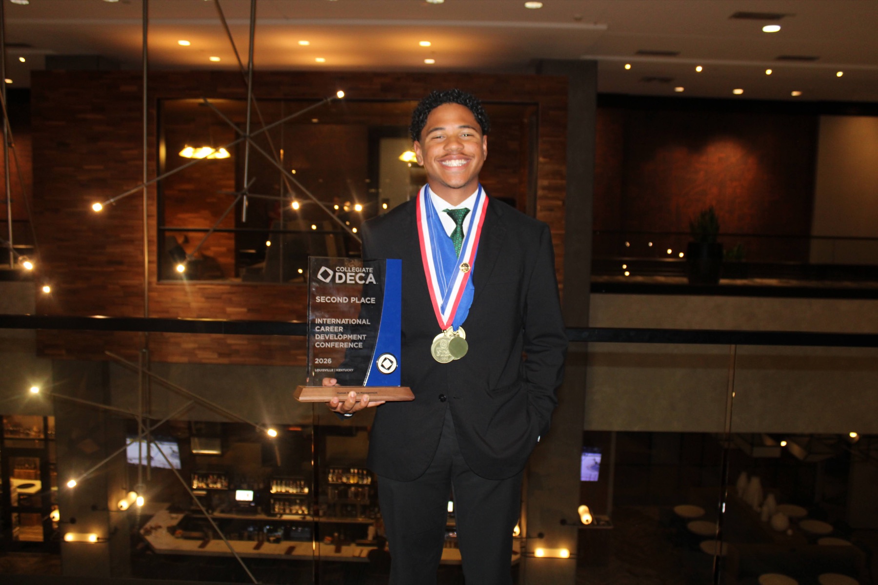 UNC Charlotte DECA member holding international second-place trophy